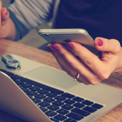 Kobieta korzysta z laptopa i telefonu, rezerwując stolik w restauracji online
